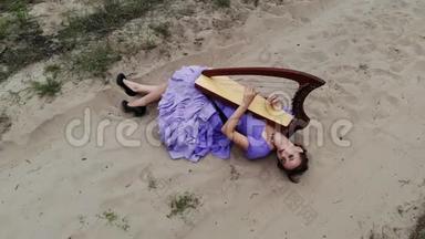 在沙漠里躺在沙滩上弹奏<strong>竖琴</strong>的女<strong>竖琴</strong>师的无人机射击。